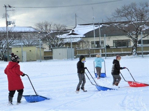 写真：校庭を雪かきする児童たち